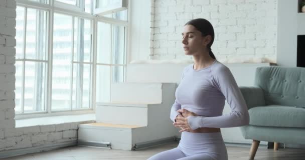 Genç mutlu kadın yoga yapıyor ve nefes egzersizleri yapıyor. Tablet üzerinde canlı video öğrenme dersleri izliyor.. — Stok video
