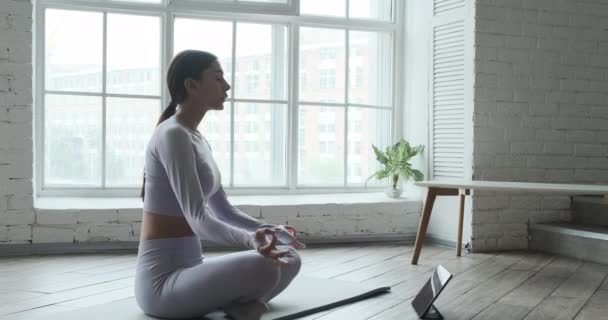 Fiatal nő meditál, használja tabletta mobil alkalmazás légzés és meditáció — Stock videók