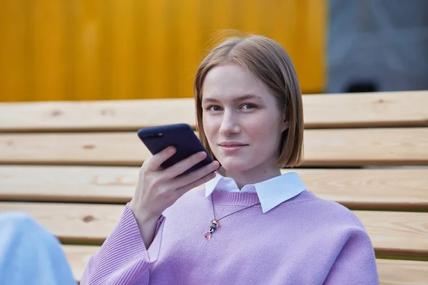 Νέα γυναίκα ξανθιά καταγράφει φωνητικό μήνυμα στο smartphone — Φωτογραφία Αρχείου