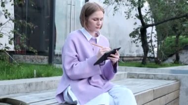 Kısa saçlı düşünceli sarışın etrafa bakıp yazıyor.