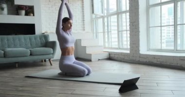 Video dersleri ve özel derslerle internetten yoga yapan mutlu genç bir kadın. 