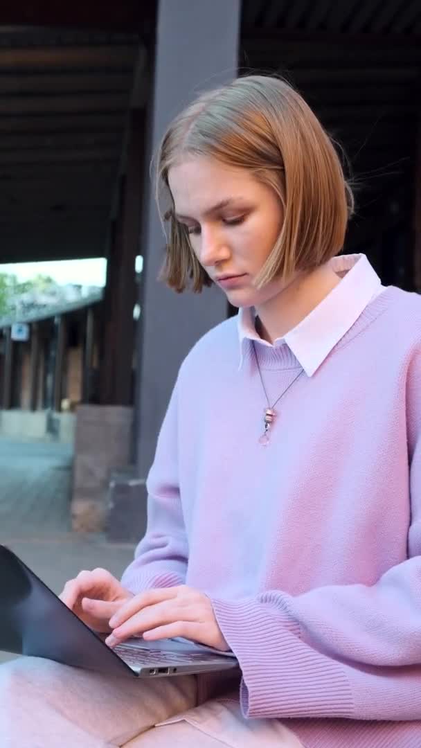 Jovem mulher em pulôver roxo mãos tipo no laptop preto — Vídeo de Stock