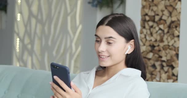 Uśmiechnięta kobieta rozmawiająca przez połączenie wideo i patrząca na telefon komórkowy. — Wideo stockowe