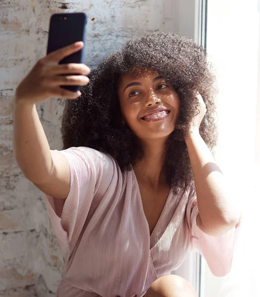 Mujer joven de raza mixta mirando la pantalla del teléfono inteligente, haciendo selfies —  Fotos de Stock