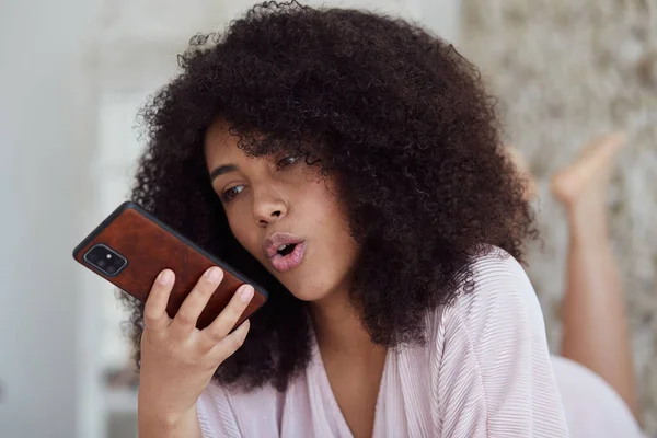 Joven mujer sonriente mixta grabando mensaje de audio a un amigo usando teléfono inteligente —  Fotos de Stock