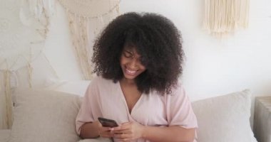 Genç Afro-Amerikan kadın akıllı telefon ekranına bakıyor komik fotoğraf ya da video izliyor