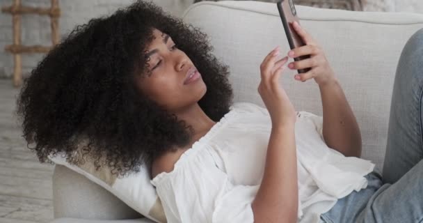 Afroamerikansk kvinna tittar på smartphone skärm titta på roliga foto, video — Stockvideo