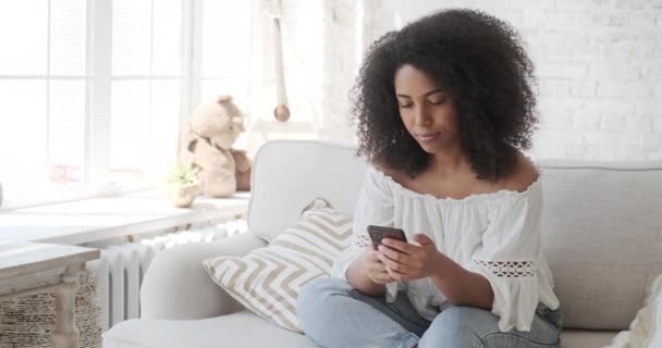 Sorrindo jovem mulher africana gostando de usar o aplicativo de smartphone lendo notícias positivas — Vídeo de Stock