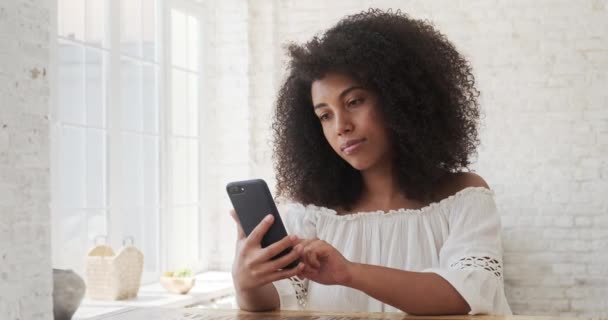 Расслабленная афро-американка, использующая приложения для мобильных телефонов, общающаяся в социальной сети. — стоковое видео