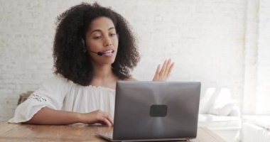 Kulaklık takan siyahi kadın internetten derse başlıyor, bir dizüstü bilgisayara bakıyor.,