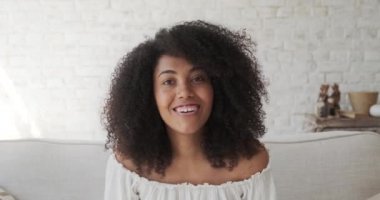 Mutlu siyah kıvırcık kadın kameraya bakıyor, arkadaşlarıyla video görüşmesinden zevk alıyor.