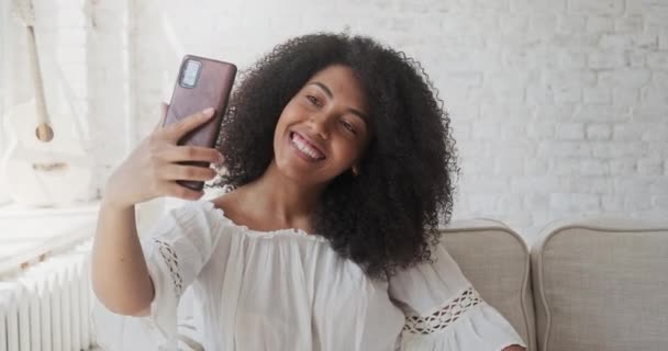 Glückliche afroschwarze Frau blickt auf Handy, winkt und grüßt. — Stockvideo