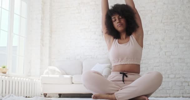 Gericht jong zwart woamn zit mat, benen gekruist, doen yoga ademhaling oefening. — Stockvideo