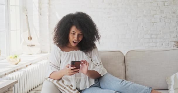 Alegre y emocionada hembra negra riendo celebrando la lotería en línea ganar, logro o ganar apuestas — Vídeo de stock