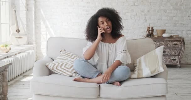 A beautiful african american woman talks on the phone with friends or colleagues, relaxes, enjoys remote communication. — Stock Video