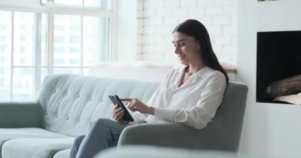 Mujer joven sonriente disfrutando usando la aplicación para teléfonos inteligentes leyendo noticias positivas — Vídeos de Stock