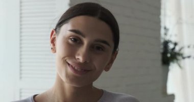 Serbest çalışan genç bir bayan tasarımcı kameraya güvenle bakar ve gülümser..