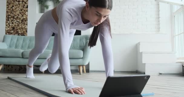 Bruneta s dlouhým culíkem se dívá na displej tabletu a cvičení — Stock video