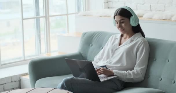 Jovem mulher em fones de ouvido usando laptop para chamada de vídeo. — Vídeo de Stock