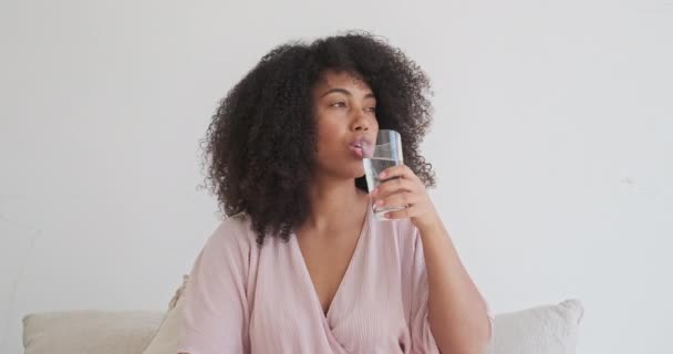 Молодая черная леди держит стакан чистой минеральной воды, улучшает здоровье и самочувствие, — стоковое видео