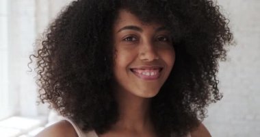 Huzurlu, genç melez bir kadın açık tenli ve gülümseyen güzel bir gülüşü var.