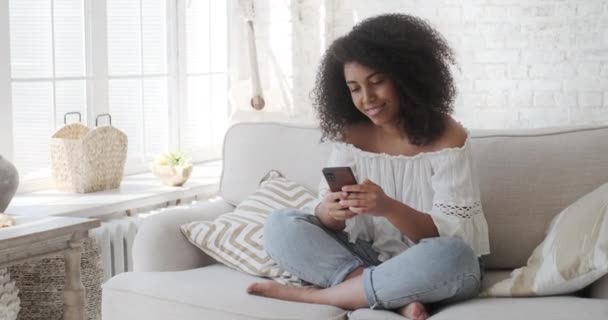Le afro amerikansk kvinna njuter av att använda smartphone ansökan läsa positiva nyheter — Stockvideo