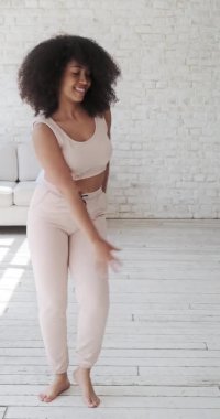 Neşeli genç melez kadın vlogger öğrencisi yalnız dans ediyor.