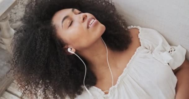 Une belle femme métissée écoute de la musique apaisante sur son téléphone et est charmée par les sentiments positifs — Video