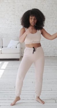 Neşeli genç melez kadın vlogger öğrencisi yalnız dans ediyor.