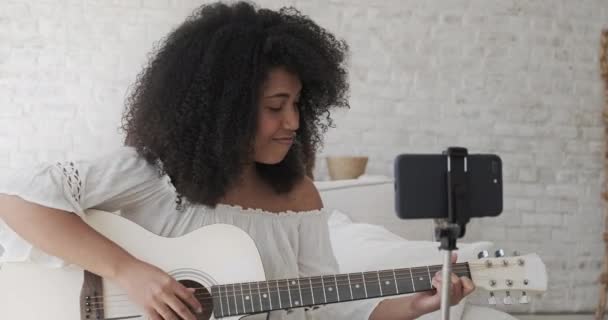 Влиятельная женщина-чёрный блогер играет на гитаре и записывает учебник, — стоковое видео