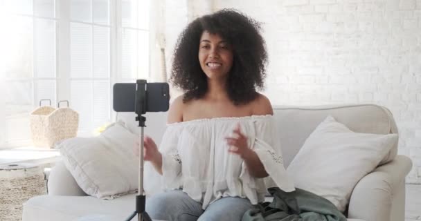 Mixed race young blogger talking about her successful purchases and shows the clothes she bought. — Stock Video