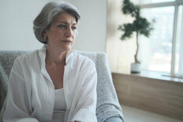 A thoughtful older woman, alone at home considering a dangerous health problem.