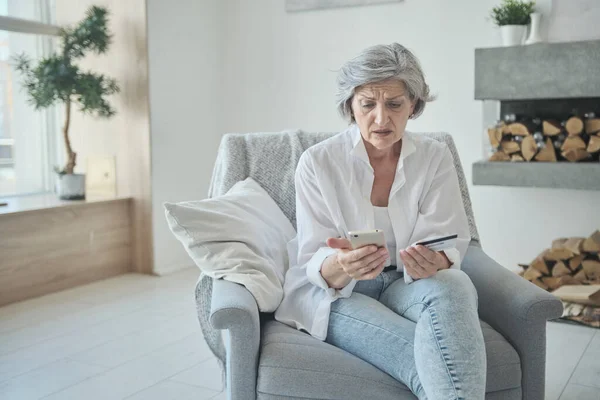 Mujer mayor caucásica usando tarjeta de crédito y teléfono móvil para compras en línea. — Foto de Stock