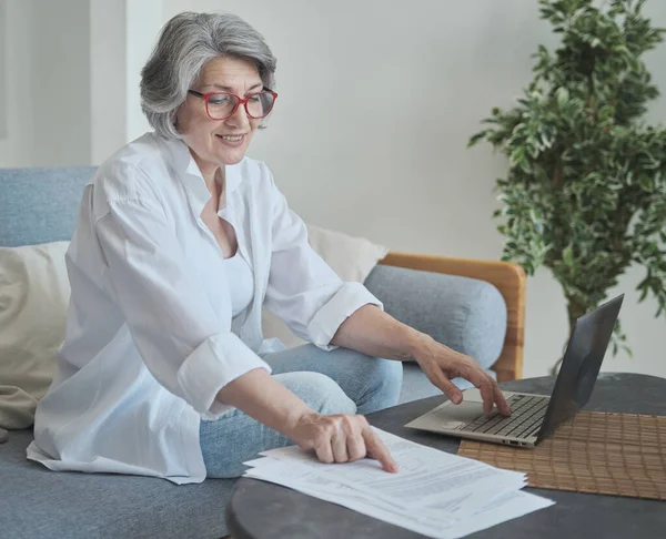 Focused senior woman using computer for research and creative work