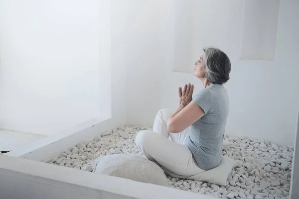 Senior gelukkige vrouw oefenen yoga en doen ademhalingsoefeningen. — Stockfoto