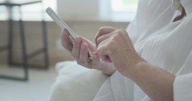 YaşIı bir bayanın yeni bir yazıyı okumak için akıllı telefon uygulaması kullanmasının yakın plan fotoğrafı.
