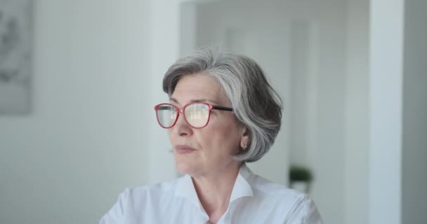 Forte anziana matura donna d'affari che indossa gli occhiali guarda seriamente la fotocamera — Video Stock