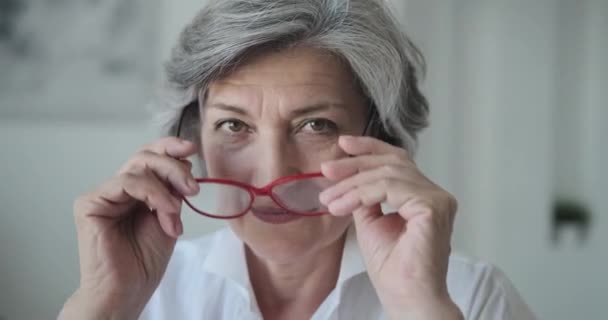 Die glückliche, ältere Unternehmerin trägt eine Brille und blickt selbstbewusst und erfolgreich in die Kamera. — Stockvideo