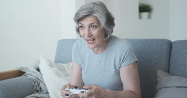 Mycket passionerad äldre person slappnar av på soffan hemma och spelar TV-spel — Stockvideo