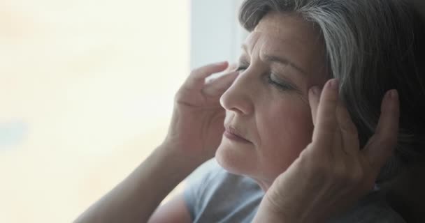 Anziani donna anziana massaggiare le tempie per ridurre il mal di testa. — Video Stock