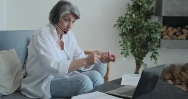Gülümseyen olgun bir kadın video ile konuşuyor ve anlatıyor ve laptopa bakıyor..