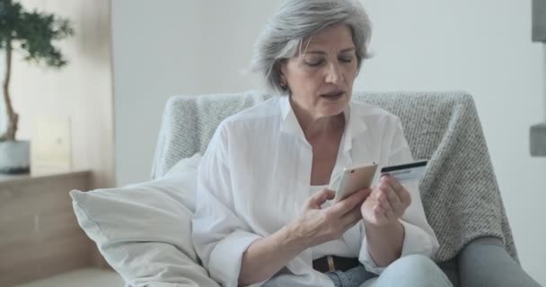 Kaukasiska äldre kvinna som använder kreditkort och mobiltelefon för näthandel. — Stockvideo