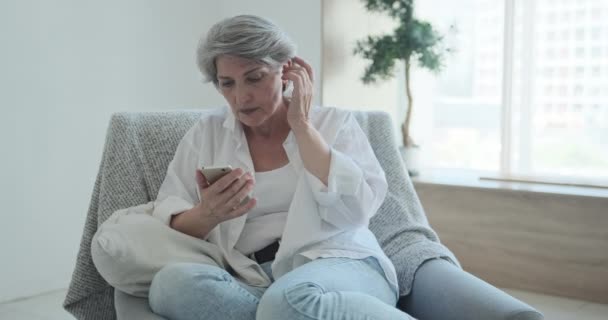 Nachdenkliche ältere Frau in den 60er Jahren, die ihr Smartphone nutzt, macht sich Sorgen über den Chat mit Kindern — Stockvideo