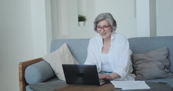 Een opgewonden oudere vrouw is actief verheugen en uiten van haar emoties over het winnen van de online loterij — Stockvideo