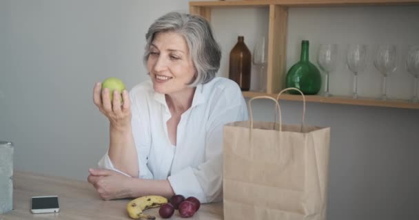 Senior vrouw kreeg levering van boodschappen in papieren zak. Online bestellen van groenten en fruit — Stockvideo