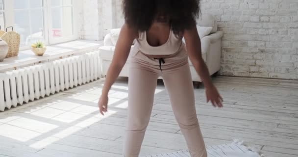 Athlétique jeune femme noire faire l'échauffement avant le tapis d'entraînement à la maison avec de grandes fenêtres le matin. — Video