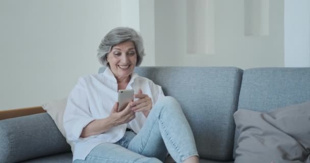 Улыбающаяся взрослая женщина 60-х годов пожилого возраста наслаждается мобильным телефоном для видеоконференции — стоковое видео