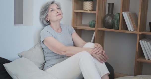 Senior atractiva dama recostada en el cómodo podio, feliz madura anciana mujer en la sala de estar — Vídeo de stock