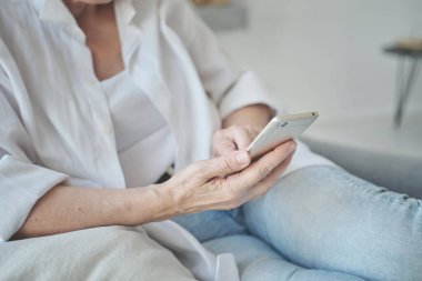 YaşIı bir bayanın yeni bir yazıyı okumak için akıllı telefon uygulaması kullanmasının yakın plan fotoğrafı.