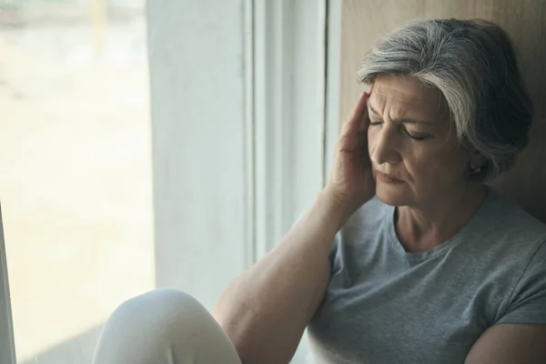 Oudere oudere vrouw masseren haar slapen om haar hoofdpijn te verminderen. — Stockfoto